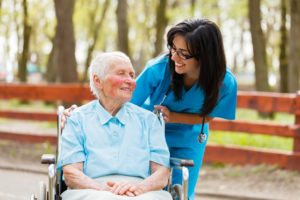 caregiver smiling with elderly person in a wheelchair